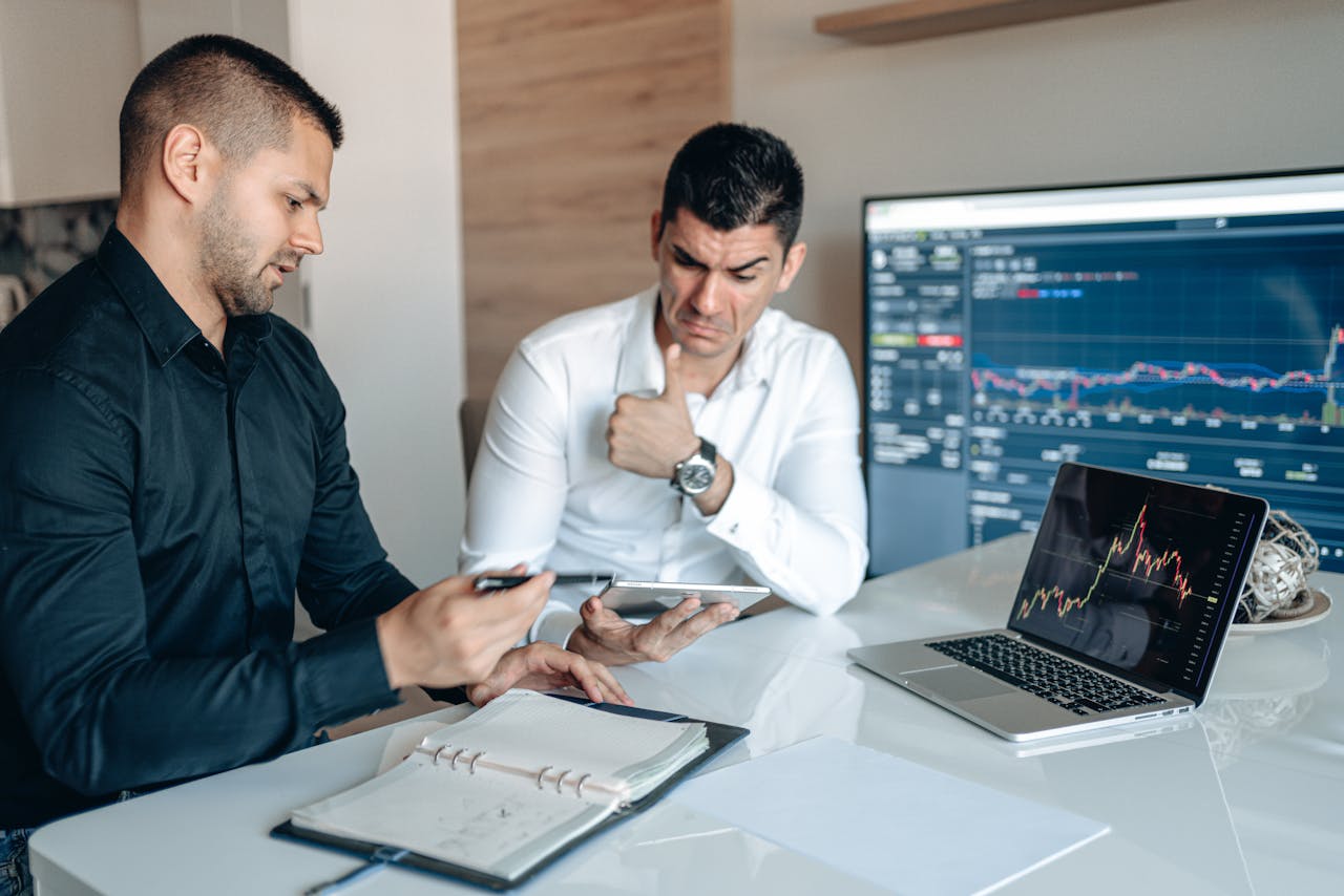 home-hero Two professionals discuss data analysis on digital devices in an office setting, focusing on graphs and charts.